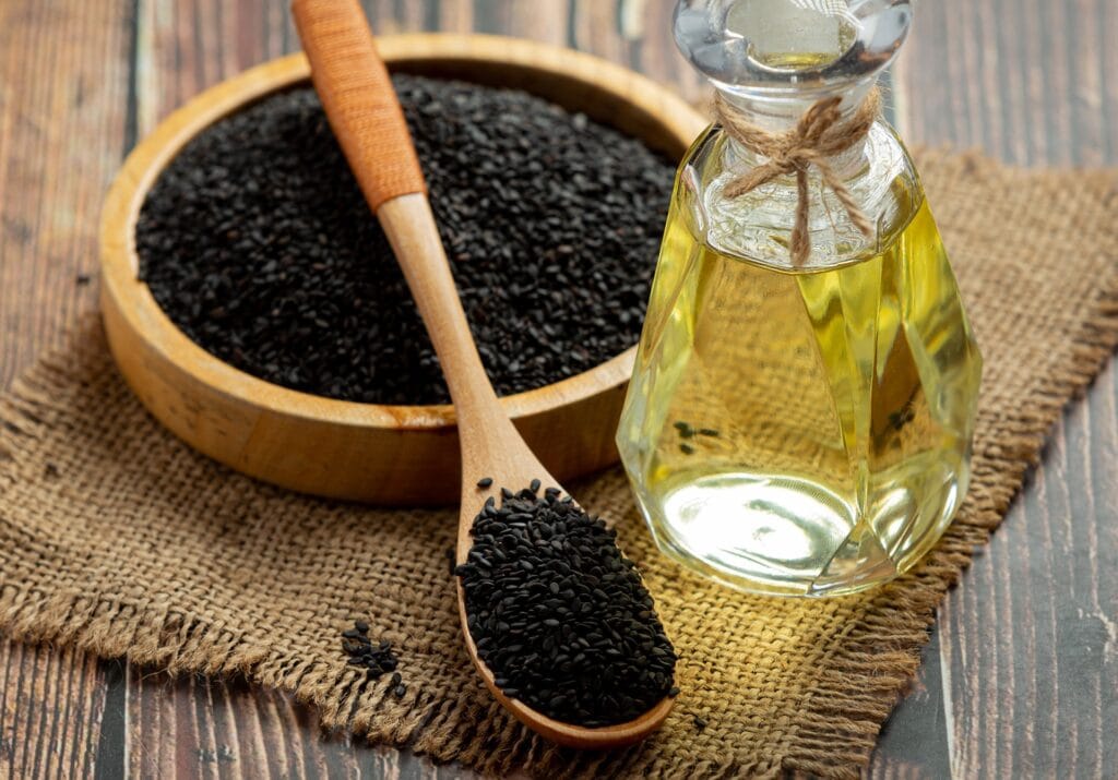 Premium cold-pressed black seed oil in amber glass bottle with Nigella sativa seeds and flower, representing high-potency volatile oil content for natural wellness support